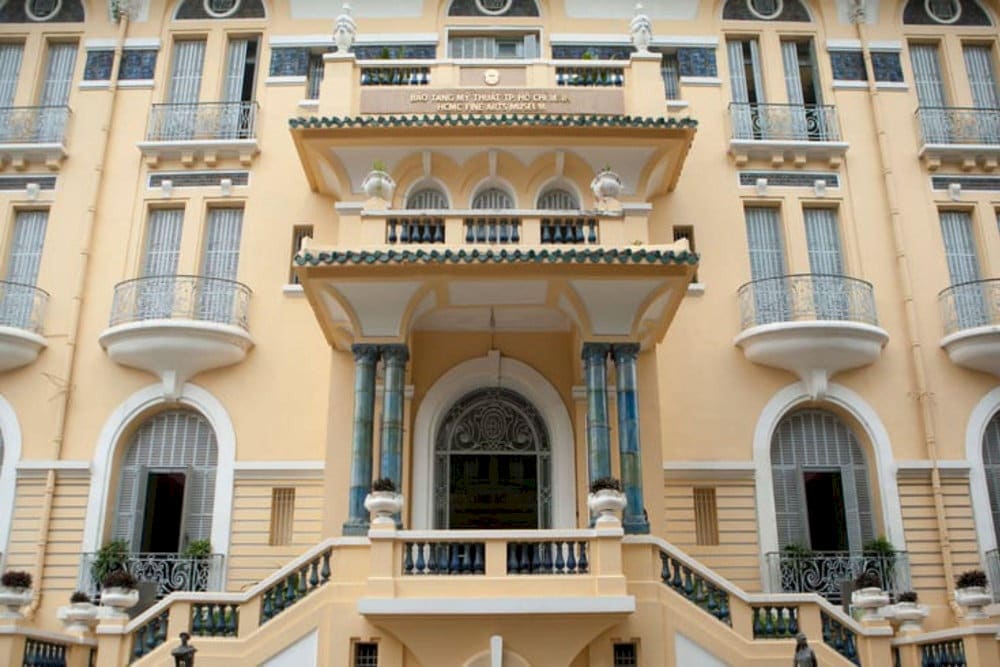 The entrance of the Ho Chi Minh City Museum of Fine Arts features a traditional design with a tiled roof and grand pillars